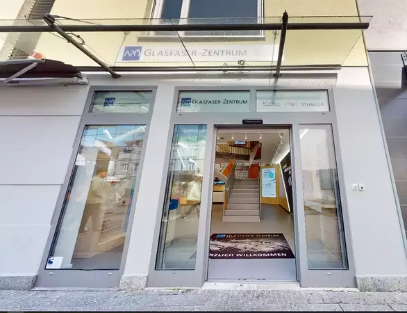 Eingangsbereich eines modernen Glasfaser-Zentrums mit heller Glasfassade und Willkommensmatte.