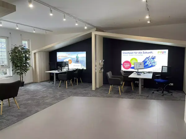 Modernes Kundencenter mit Beratungsecken und Werbetafeln für Glasfaser-Internet.